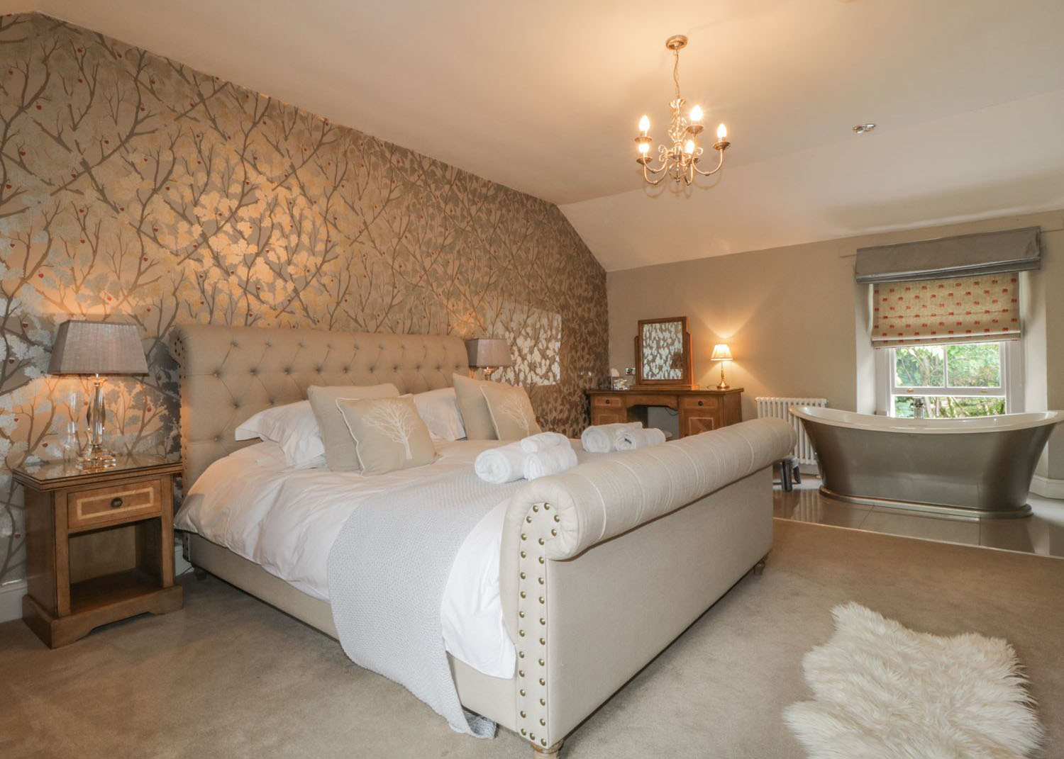 Double bed in an elegant bedroom featuring a roll top bath tub and electricals