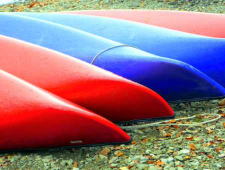 An image of 5 beached canoes on the Lakeshore in the Lake District