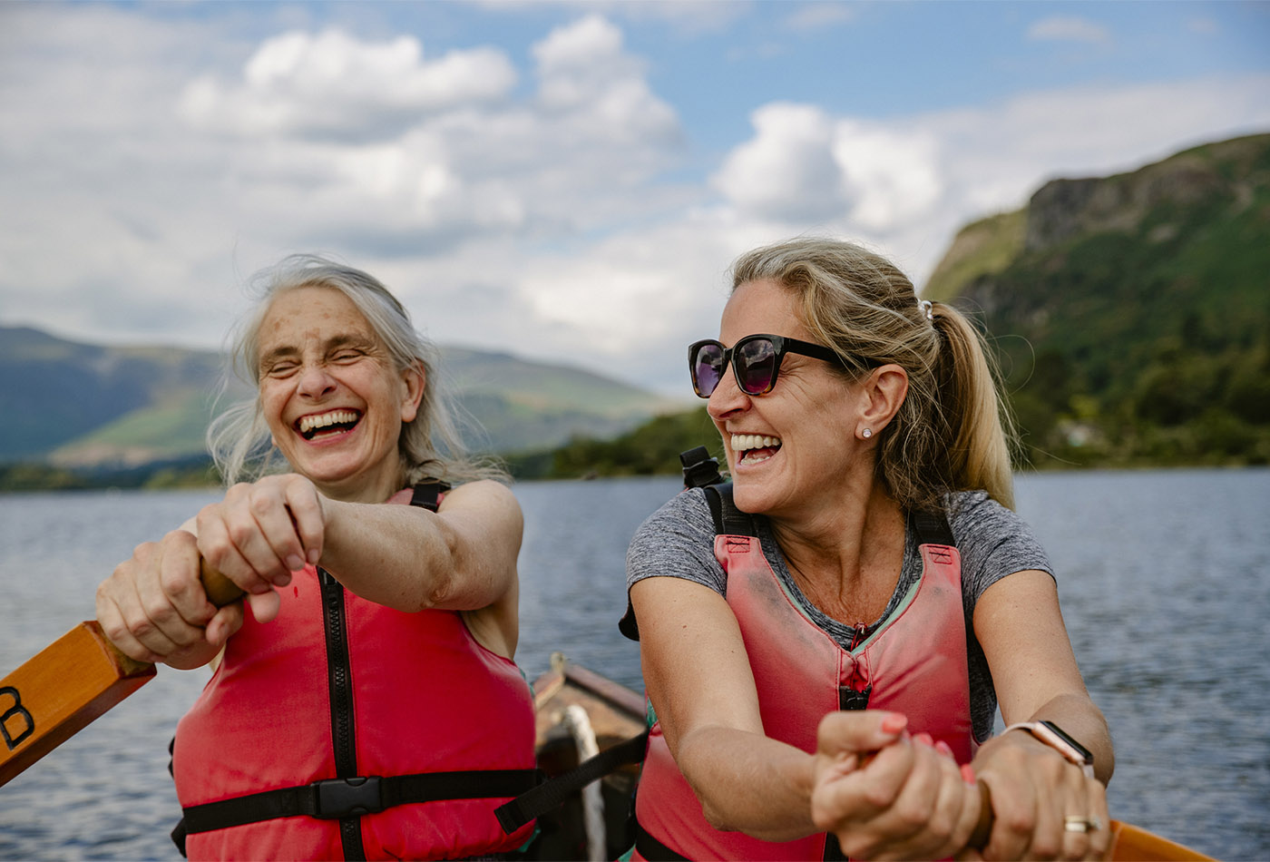 An older mother and daughter having fun in a rowing boat on Derwent Water in The Lakes District in Cumbria