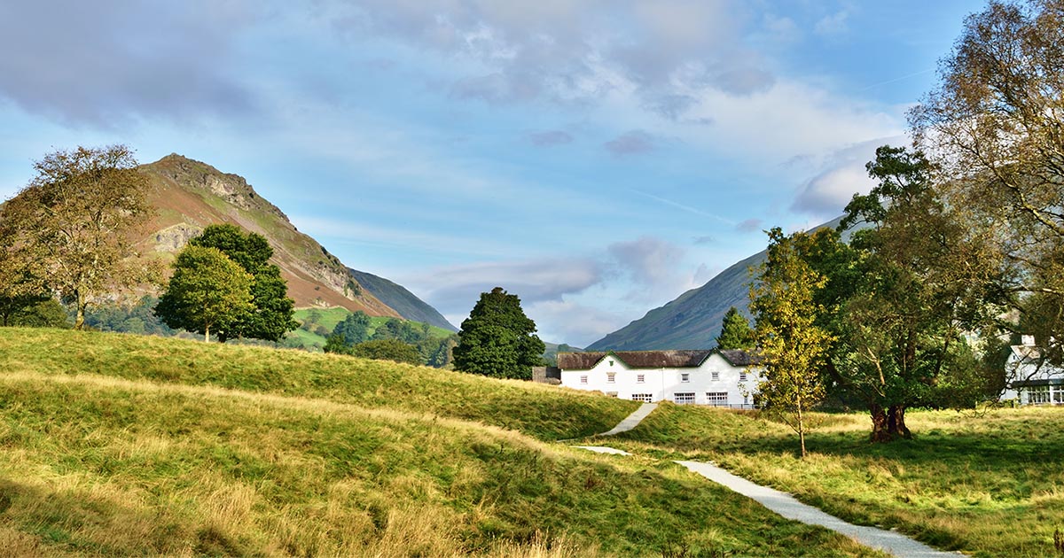 A path winding its way through green fields, from Grasmere, towards Helm Crag, on a tranquil summers day in the English Lake District.
